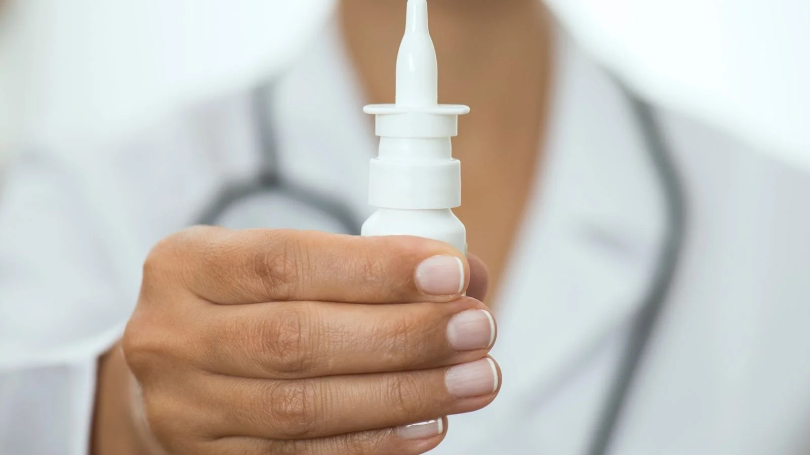 A person holds up a nasal spray bottle.