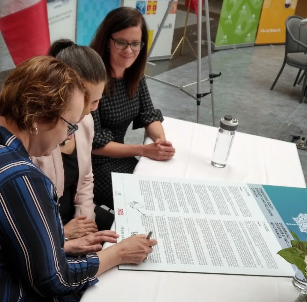 Laurier President Deborah McLatchy, Minister of Science Kirsty Duncan, and Diana Parry sign the charter document.