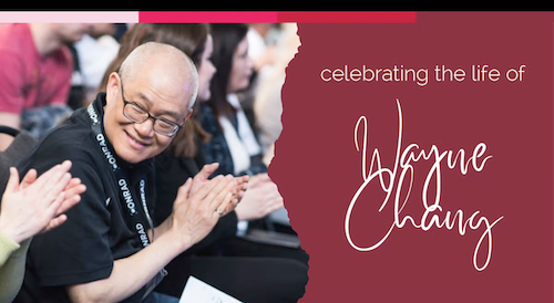 Wayne Chang claps as he is seated next to students.