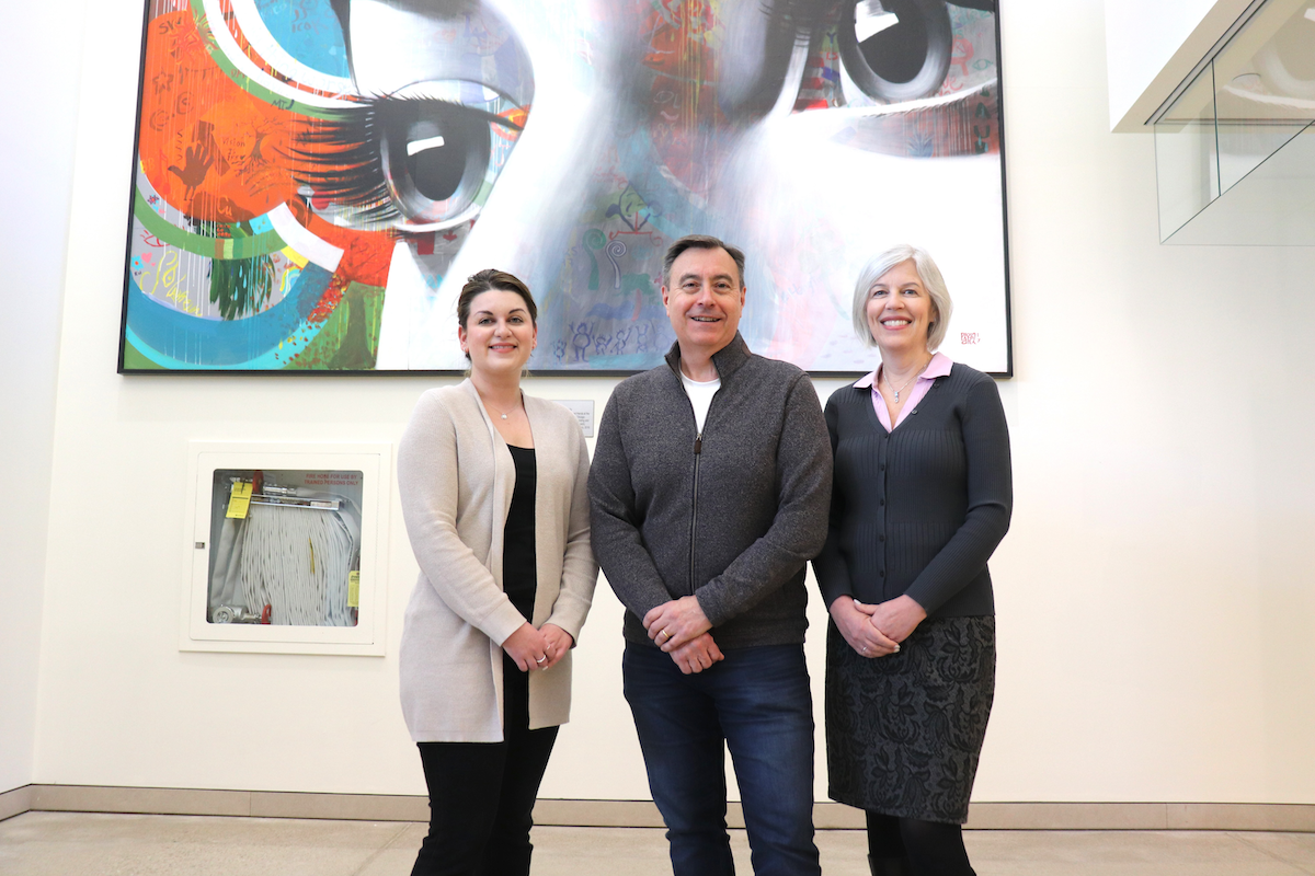 Drs. Chelsea Bray, Lyndon Jones and Jill Woods stand in front of a piece of artwork.