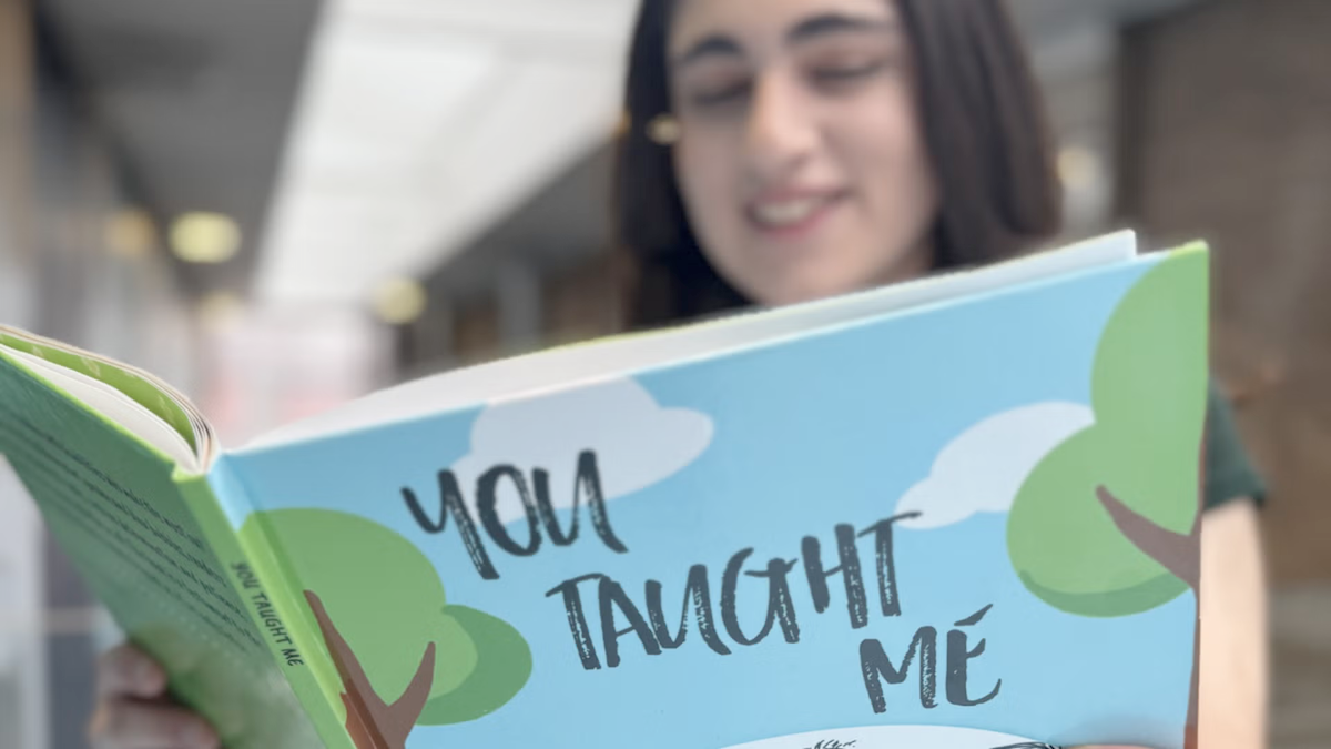 Talina Papazian holds open a copy of her book "You Taught Me."