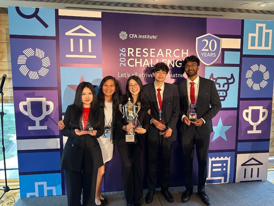 Five members of the student team stand against a CAF Research Challenge board.