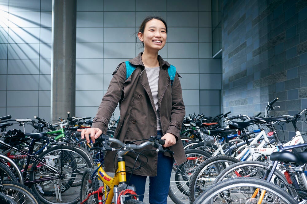 Woman holding bike handlebars smiling.