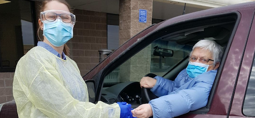 Dani Thomas takes blood from a patient in a car.