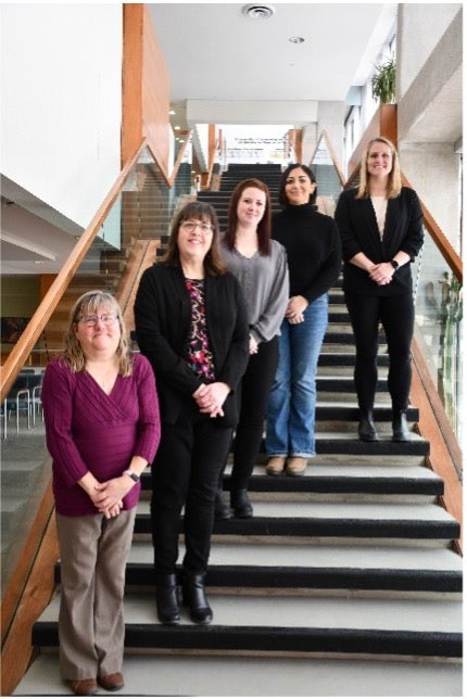 Deb Iler and her colleagues stand on stairs in the Tatham Centre.