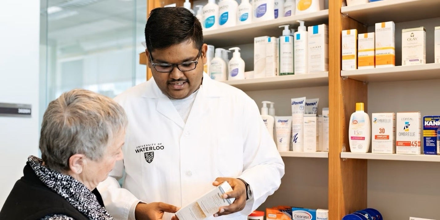 A pharmacist in a white coat assists a patient.
