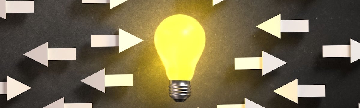 A lit light bulb with arrows on either side of it.