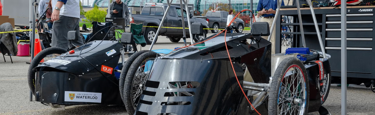 Two electric racecars parked with the Davis Centre in the background.