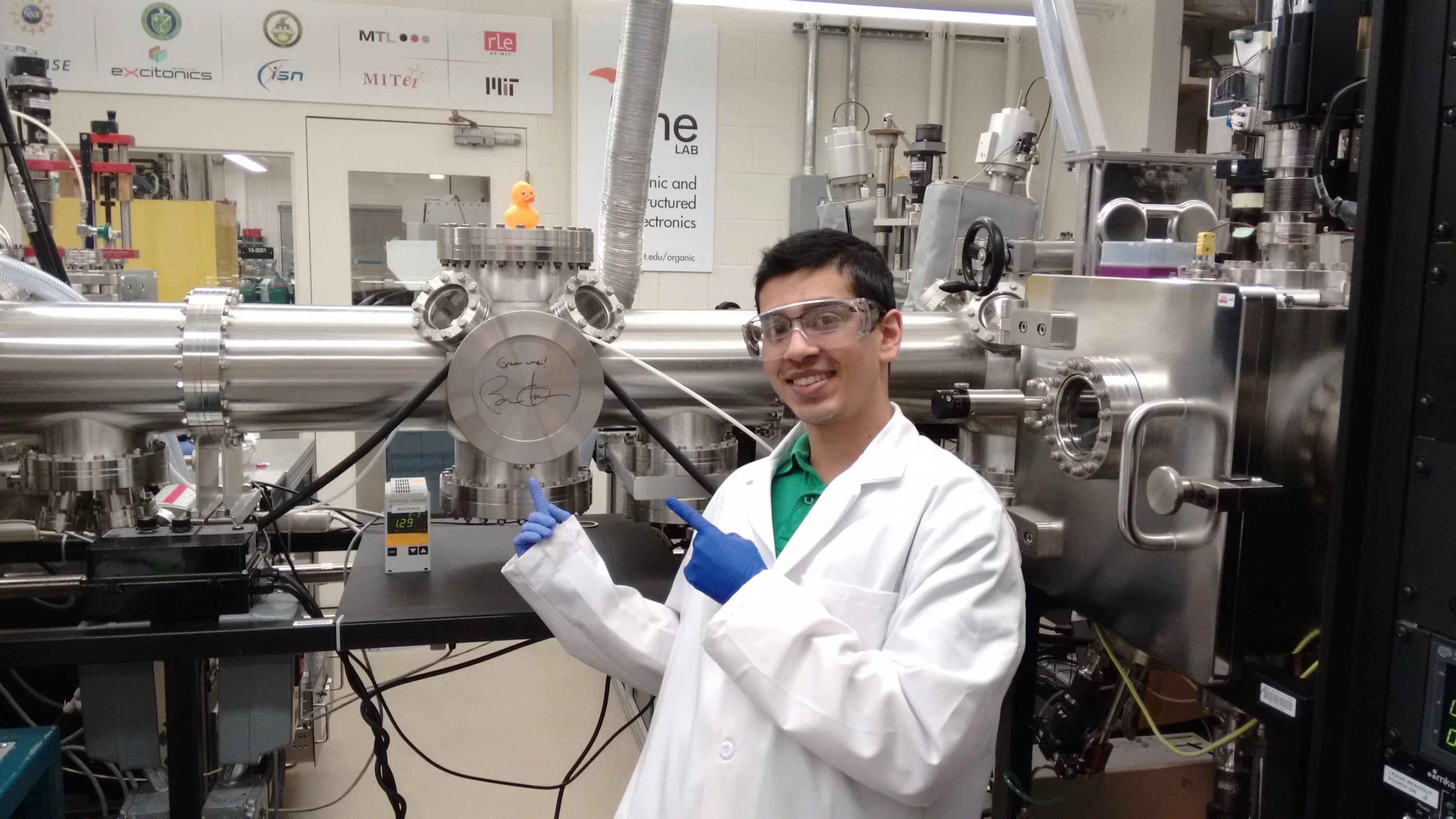 Jatin Patil in a lab next to a piece of equipment signed by President Barack Obama.