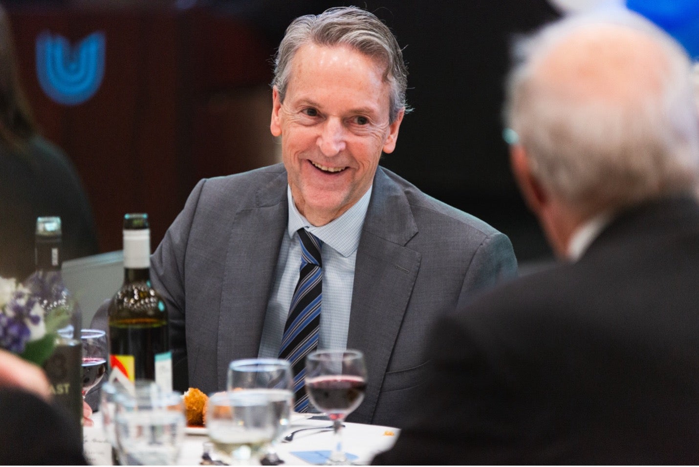 Principal Richard Myers smiles as he sits at a round table at a dinner event.