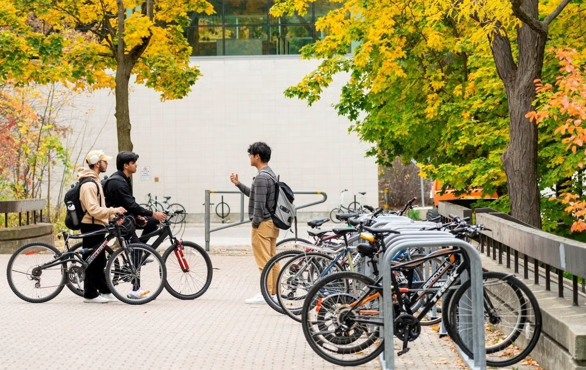 Students stand near bike racks on campus.