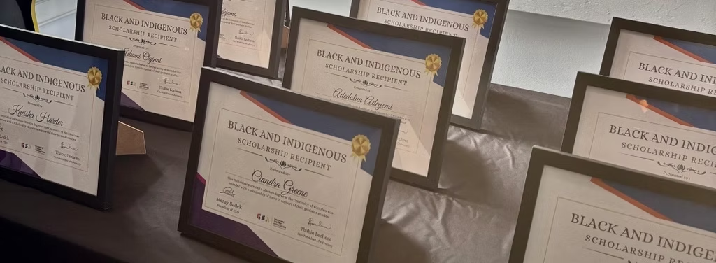 A number of framed Black and Indigenous award certificates on a table.
