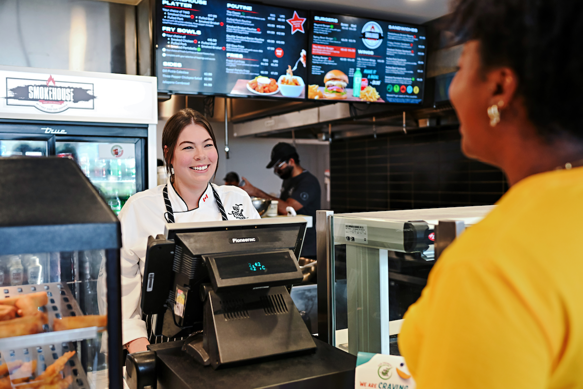 A smiling UW Food Services employee helps a customer at the cash register of the Smokehouse.