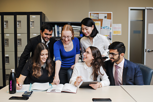 Lecturer Diana Skrzydlo with several students at a desk.