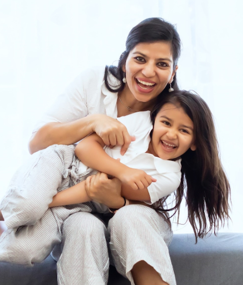 A smiling mother and daughter sitting together.