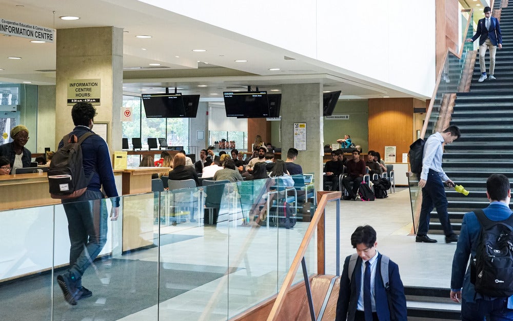 Students walk through the Tatham Centre and sit waiting for a co-op interview.