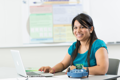 A young woman sits at a laptop.