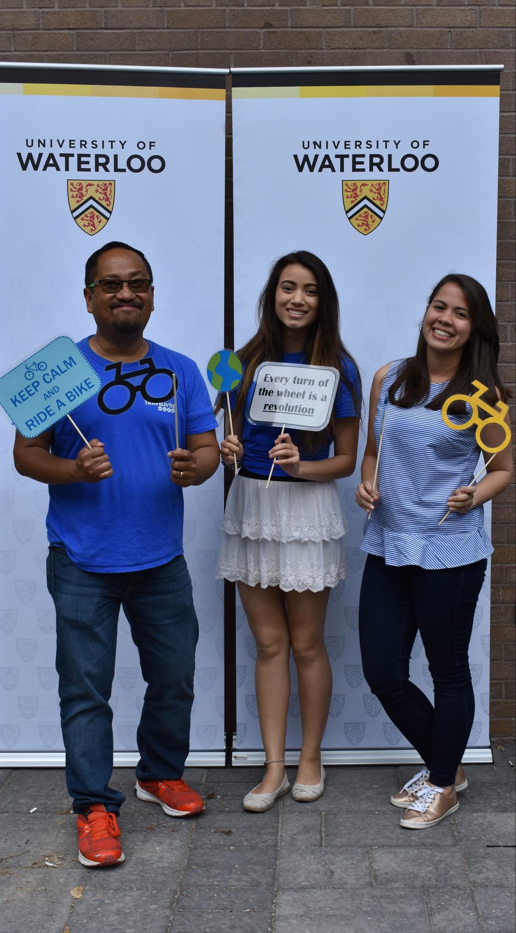 Three people hold bike-related signs.