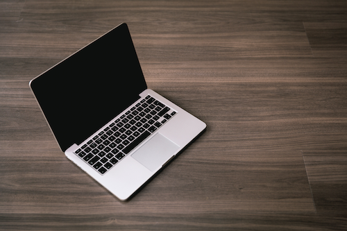 An unplugged, shut down laptop on a wooden table.