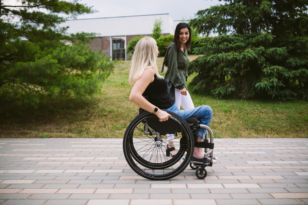 Woman in wheelchair next to woman standing on UW path