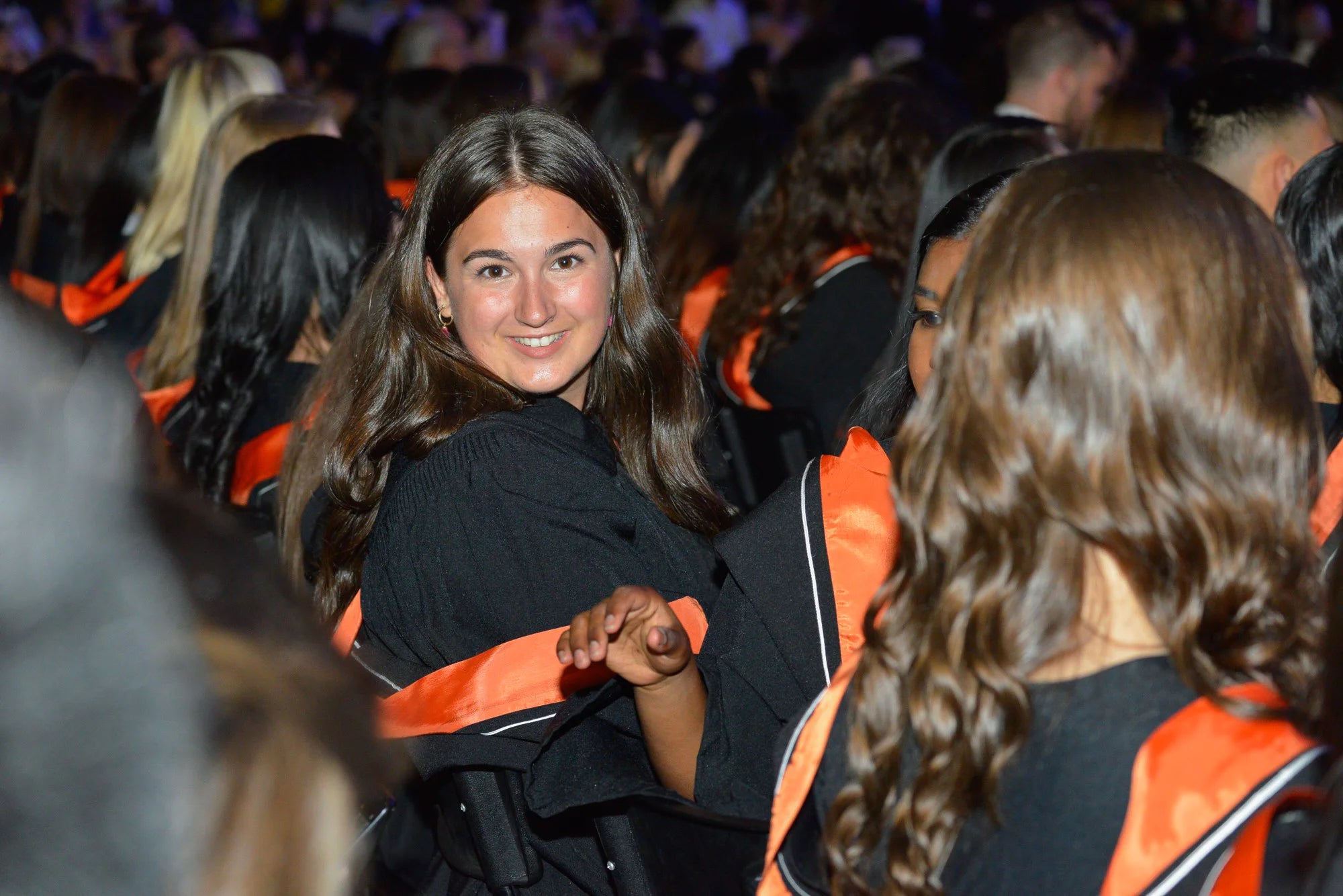 An Environment graduand smiles in the Convocation audience.