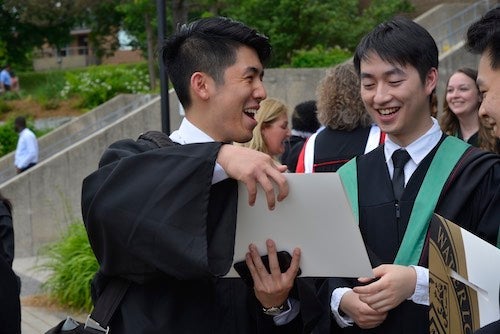 Students compare diplomas at the 2018 Arts convocation ceremony.