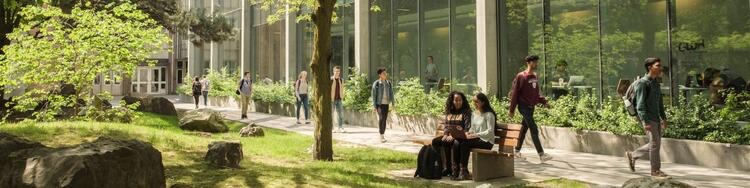 Students sit and walk in campus green space.