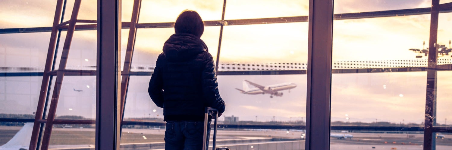 Someone looking out the window at an airport at an airplane.