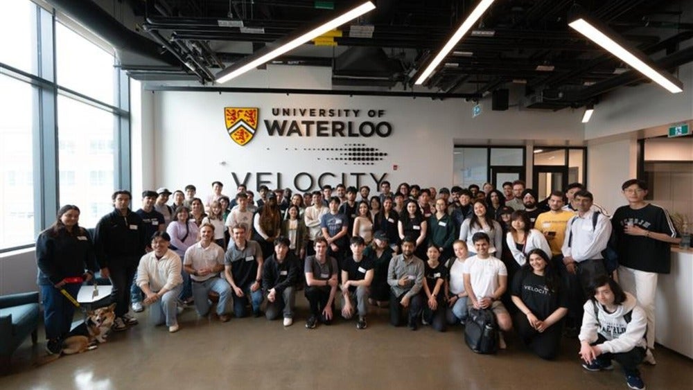 Group of people pose in front of wall featuring a University of Waterloo logo and a Velocity logo.