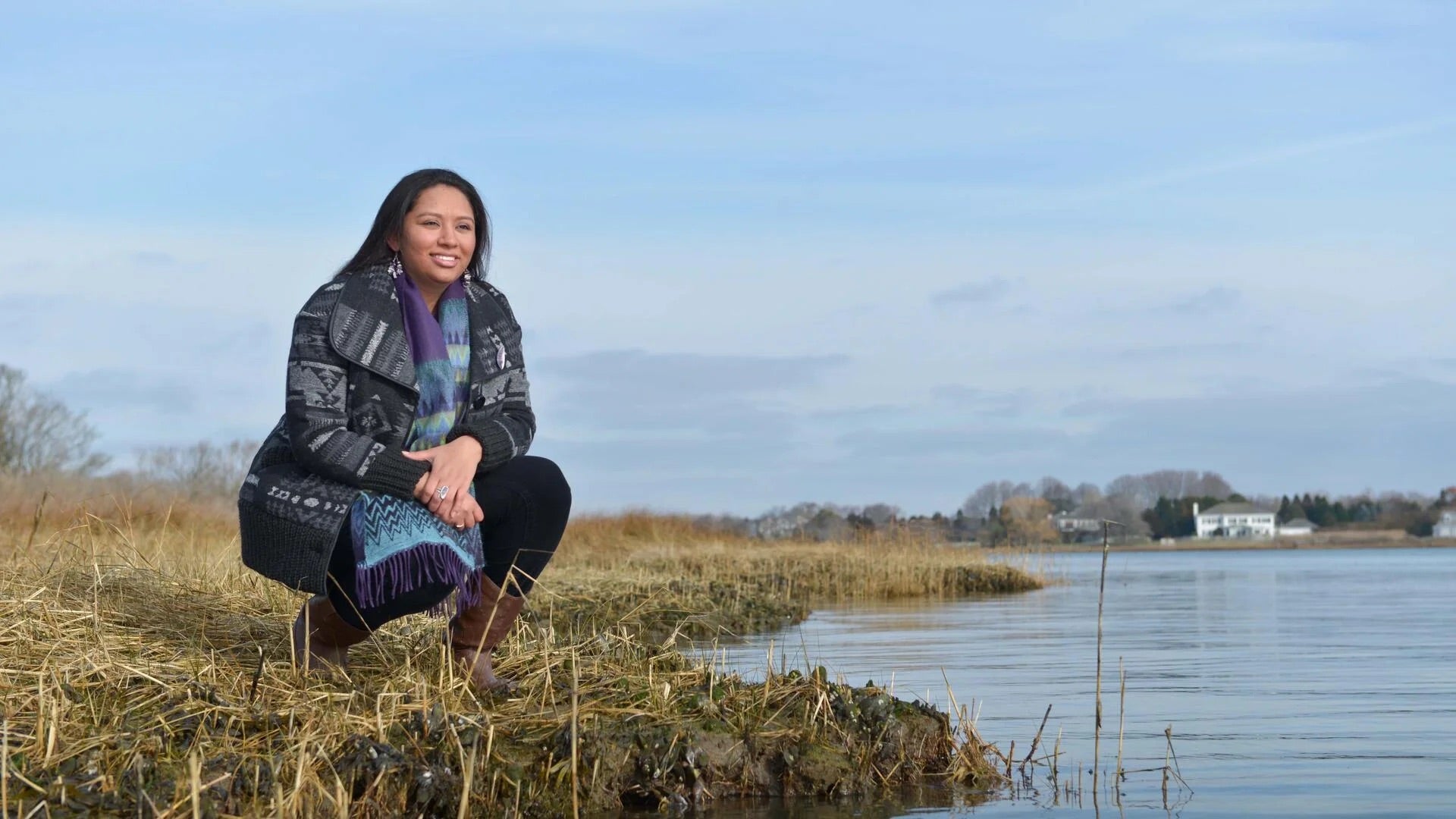 Kelsey Leonard sitting at the edge of a lake.