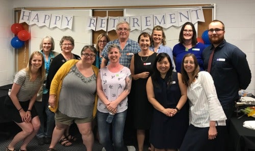 A group photo celebrating John Varon at his retirement party.