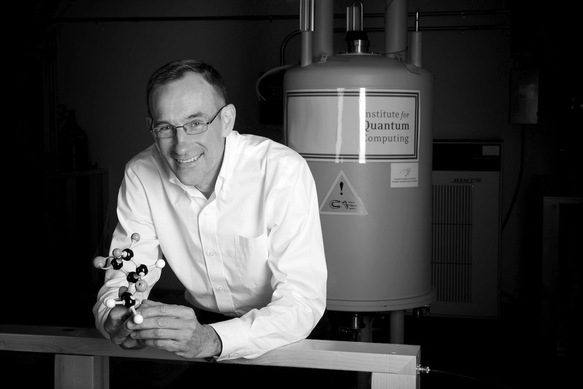 Dr. Raymond Laflamme holds a scale model of an atom in an IQC lab.