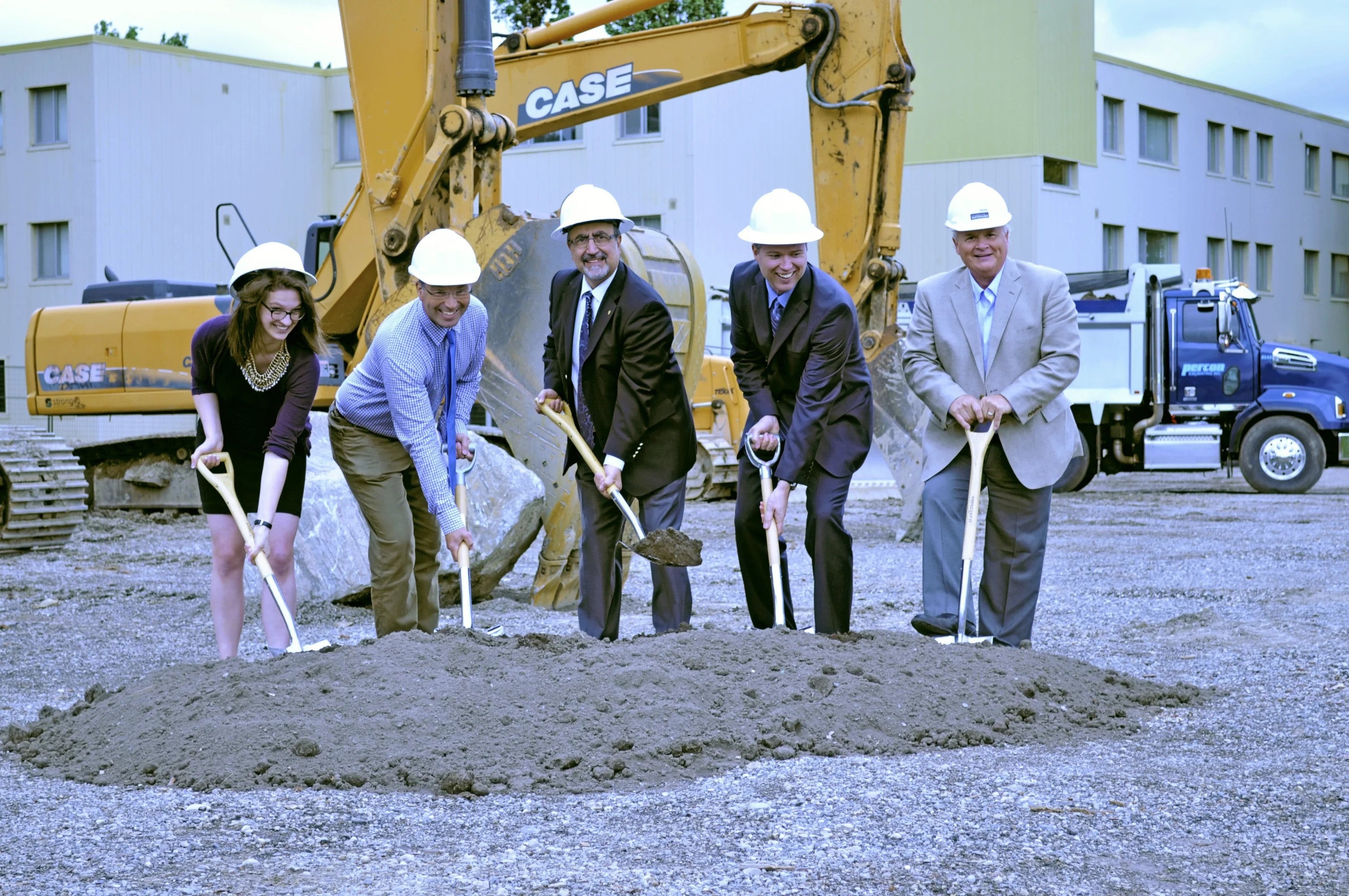 Waterloo representatives plant shovels in the dirt at the residence groundbreaking ceremony.