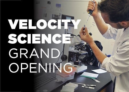 A person performs a science experiment with the words "Velocity Science Grand Opening" superimposed.