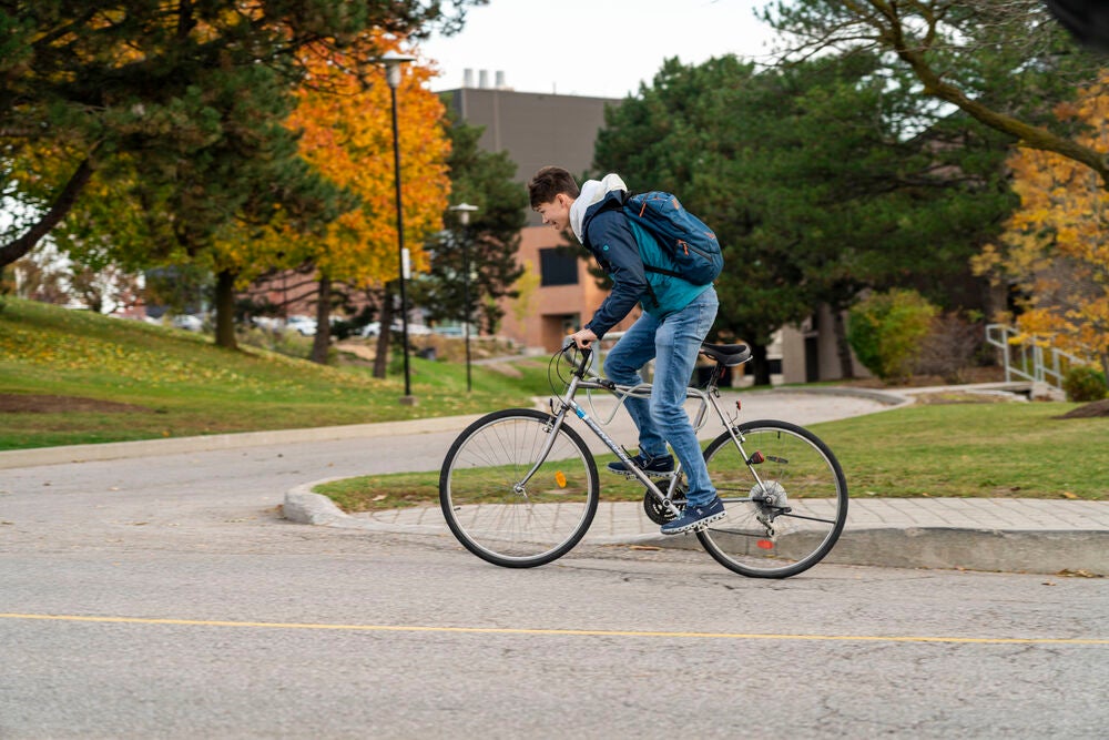 Student rides a bike up Ring Road.