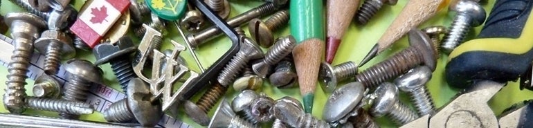 A jumble of screws, bolts, pencil crayons and a University of Waterloo pin.