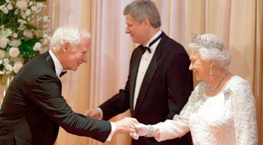 David Johnston shakes hands with Queen Elizabeth while Stephen Harper stands in the background.