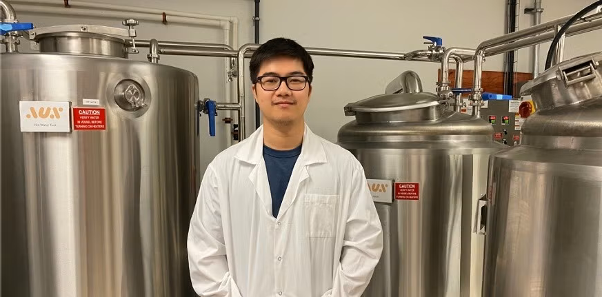 Matthew Li standing in front of lab equipment.