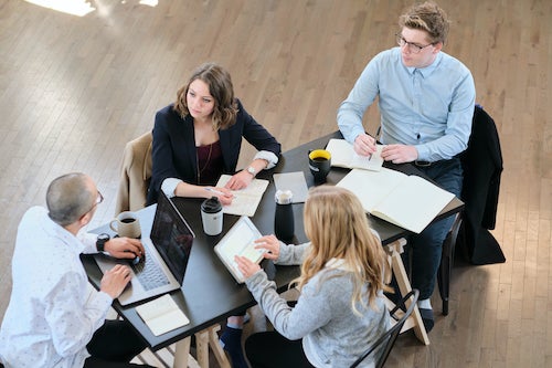 A group of employees meet around a table.