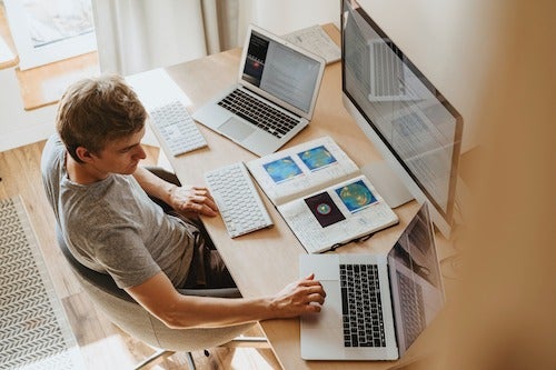 A man sits in front of a large number of computer peripherals.