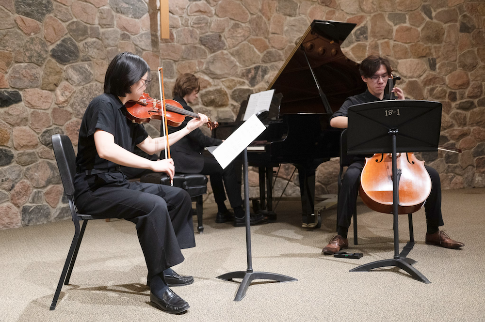 A violin, cello, and piano player performing together.