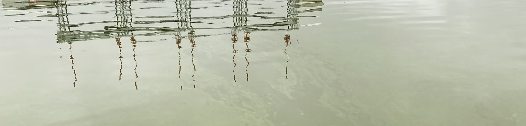 A dock reflects back on a cloudy water's surface.