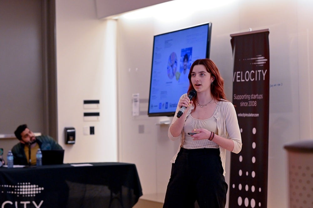 A woman presents in front of a Velocity banner.