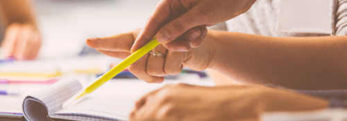 A person makes a note with a pencil on a pad.