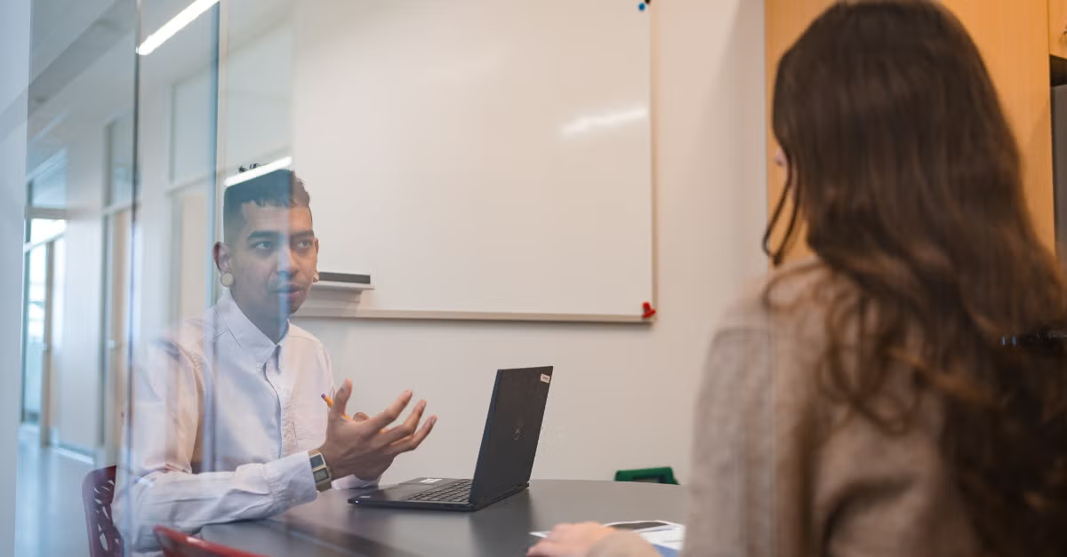 Two people converse while seated at a table.