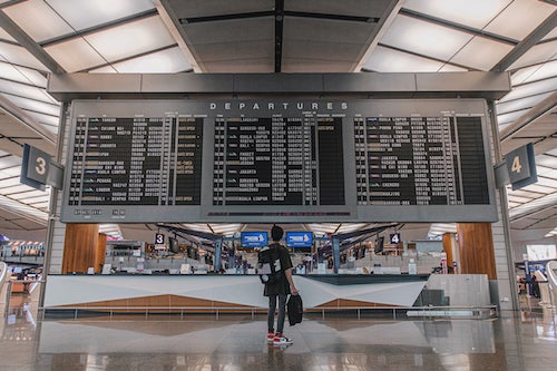 A person looks up at an airport departure screen.