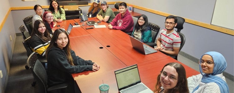 Co-op students hired to assist with the WCMS transition sit around a table.
