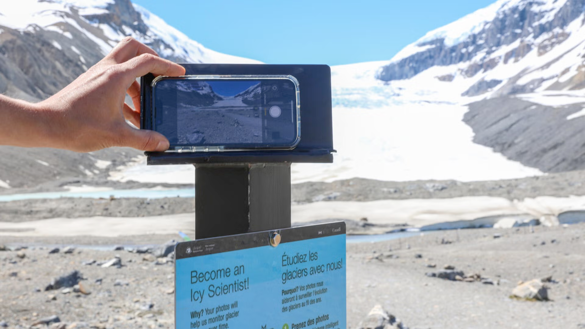 A person mounts a smartphone on a tripod to take a photo of a glacier.