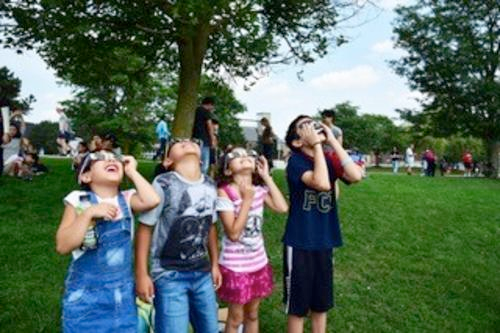 Children view eclipse through eclipse glasses.
