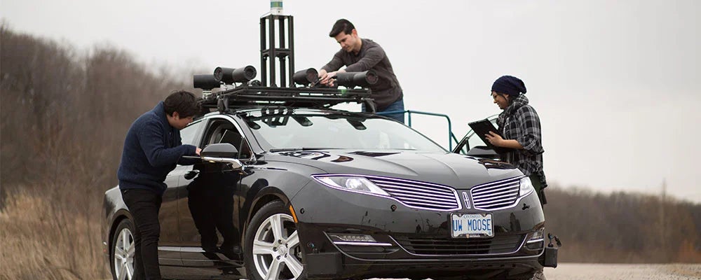 Three students work on an alternative fuel vehicle.